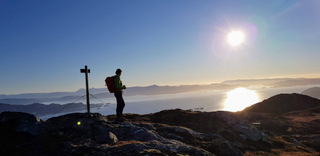 På Tøsdalsfjellet. Solen speiler seg i Bjørnefjorden